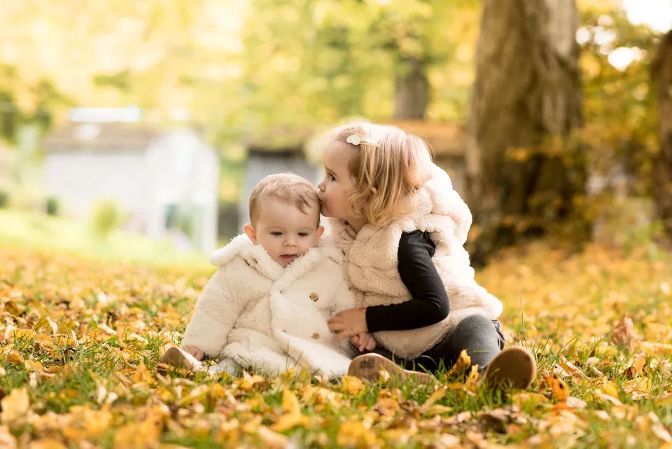 Deux enfants assis dans l'herbe en automne